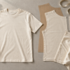 Plain cream T-shirt beside fabric panels, paper patterns, scissors and measuring tape.